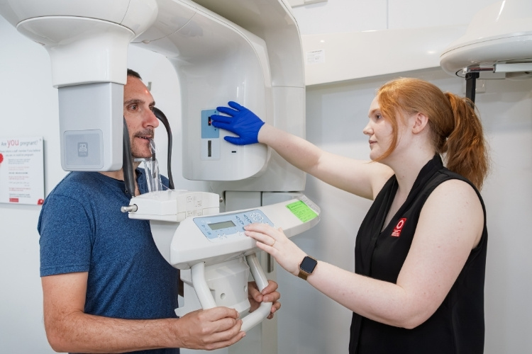 Radiographer prepares to take OPG dental X-ray for male patient.