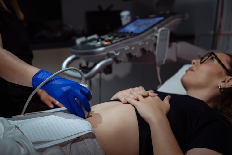 Sonographer does pregnancy ultrasound imaging on patient.