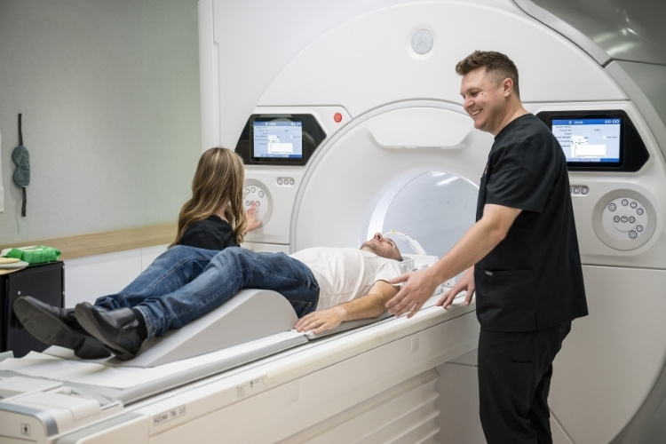 Two MRI technologist start patient sliding into an MRI scan.